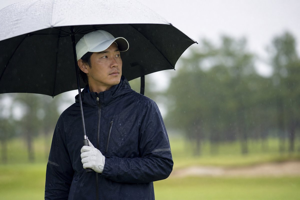 雨のゴルフ場でレインウェアを着たゴルファー