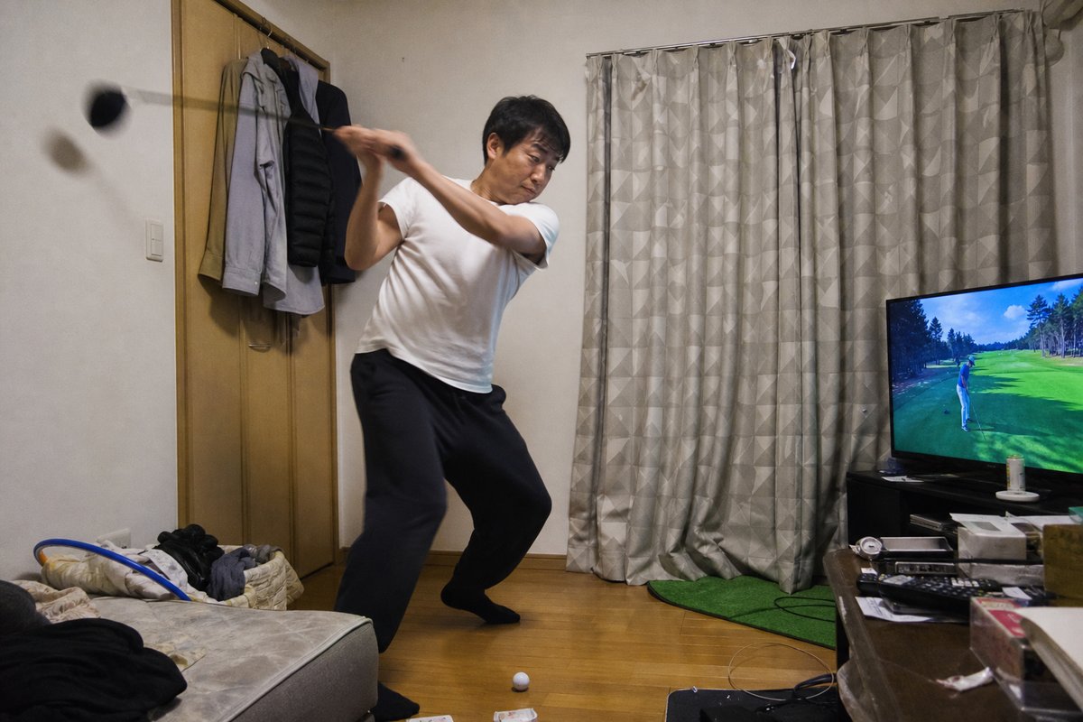 リビングで雑に素振りする男性