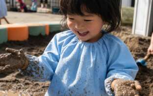 撥水プレイウェアで泥遊びする子ども