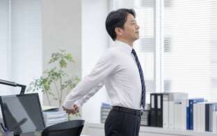 デスクで肩を伸ばす男性