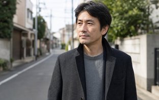 冬の日本の街で、ウールのコートとニットを着た40代の日本人男性